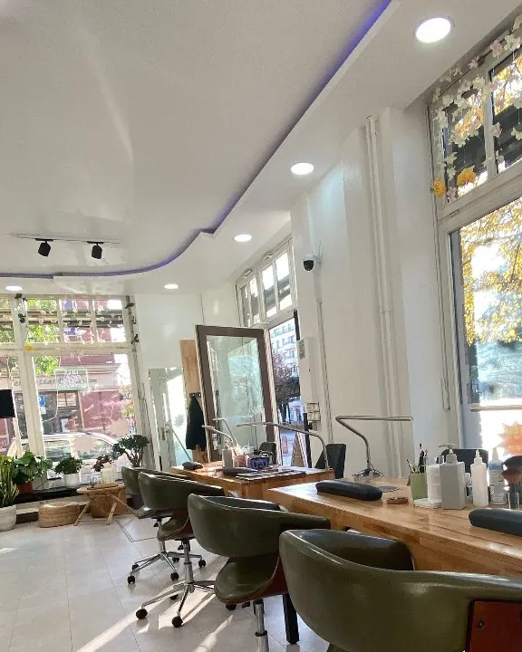 Heller Salon mit großen Fenstern, Holztisch und Pediküre-Sesseln